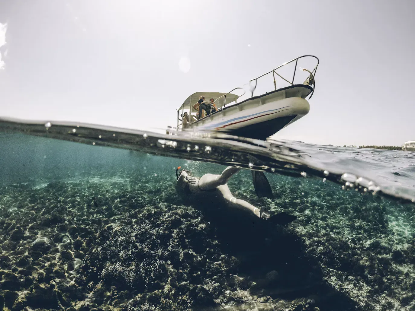 Snorkeler exploring a coral reef beside a tour boat in Lembongan, Indonesia